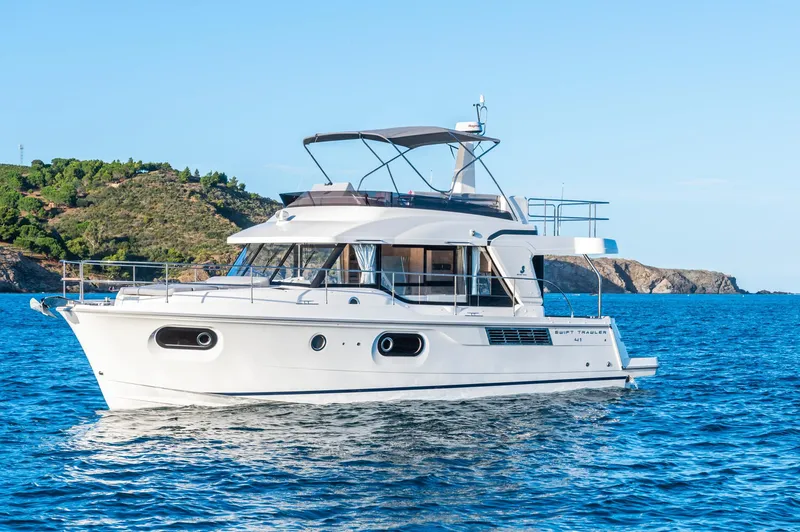 Slide: The Image of 2025 Beneteau Swift Trawler 41 Fly cruising on blue ocean near rocky coastline. - 18