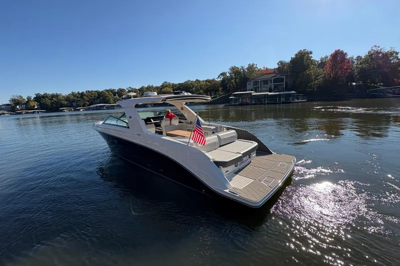 Slide: The Image of 2023 Sea Ray SLX 400 boat cruising on a serene lake with lush greenery. - 2