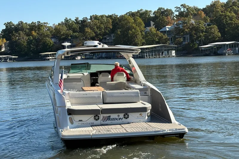 Slide: The Image of 2023 Sea Ray SLX 400 boat cruising on a serene lake with docked boats in the background. - 4
