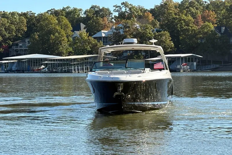 Slide: The Image of 2023 Sea Ray SLX 400 boat cruising on a calm lake with trees in the background. - 54