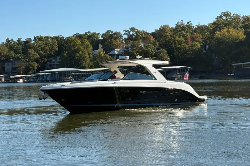 Slide: The Image of 2023 Sea Ray SLX 400 boat cruising on a lake with trees and docks in the background. - 55