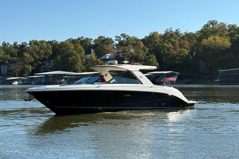 Slide: The Image of 2023 Sea Ray SLX 400 boat cruising on a calm lake with trees in the background. - 56