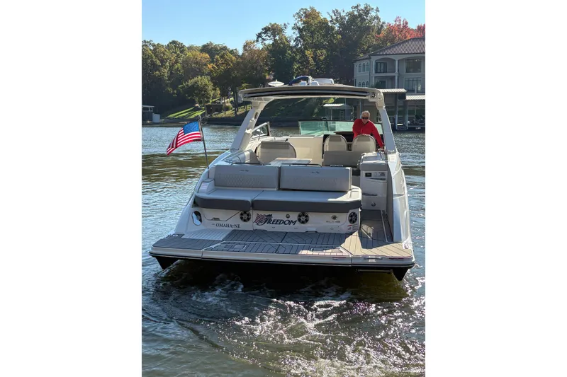 Slide: The Image of 2023 Sea Ray SLX 400 boat cruising on a lake with American flag. - 59