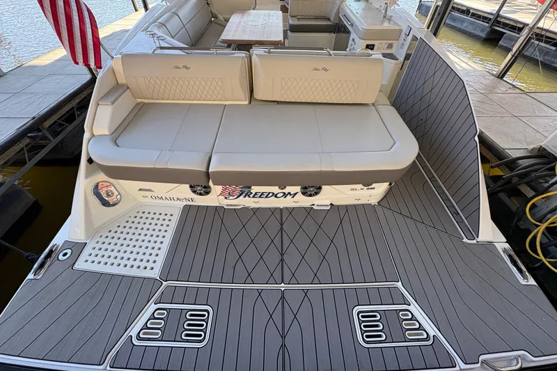 Slide: The Image of 2023 Sea Ray SLX 400 luxury boat docked with American flag, spacious seating, and elegant design. - 9