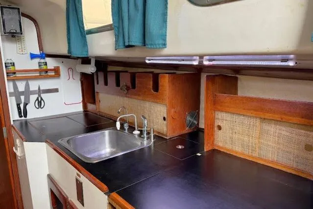 Slide: The Image of 1965 Pearson Alberg 35 yacht interior kitchen with sink, wooden cabinets, and utensils. - 9