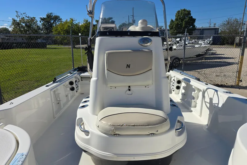 Slide: The Image of 2017 NauticStar 215 XTS boat interior with seating and console, parked outdoors. - 15