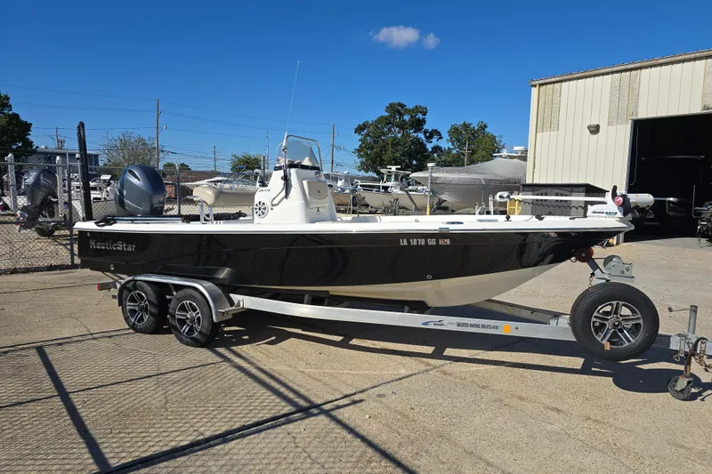 Slide: The Image of 2017 NauticStar 215 XTS boat on trailer, parked outdoors under clear blue sky. - 5