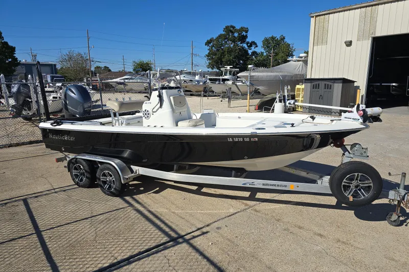 Slide: The Image of 2017 NauticStar 215 XTS boat on trailer, parked outdoors near a storage facility. - 6