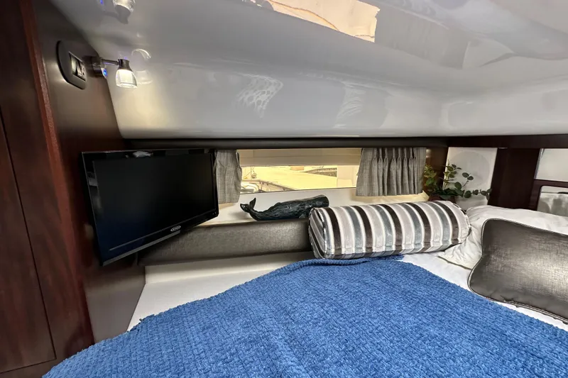 Slide: The Image of 2020 Monterey 355 Sport Yacht interior cabin with TV, bed, and window view. - 44