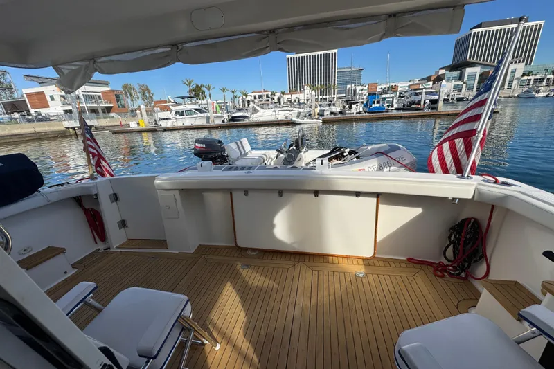 Slide: The Image of 1998 Bayliner 4788 Pilot House Motoryacht docked, featuring spacious deck and American flags. - 63