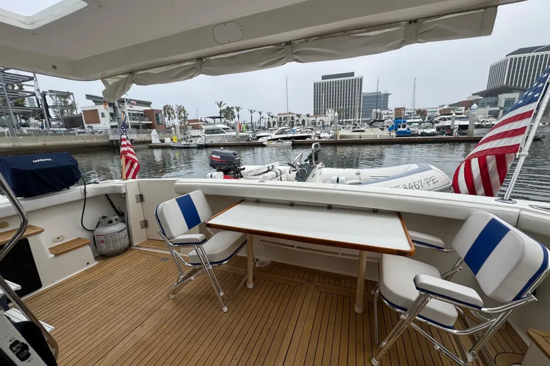 Slide: The Image of 1998 Bayliner 4788 Pilot House Motoryacht with deck seating, table, and American flags in marina. - 8