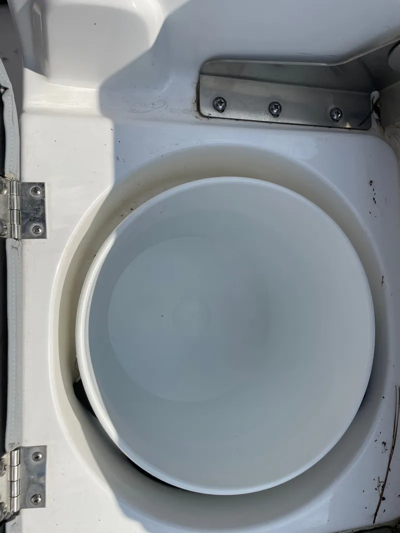 Slide: The Image of 2024 NauticStar 191H boat compartment with circular storage area and metal hinges. - 12