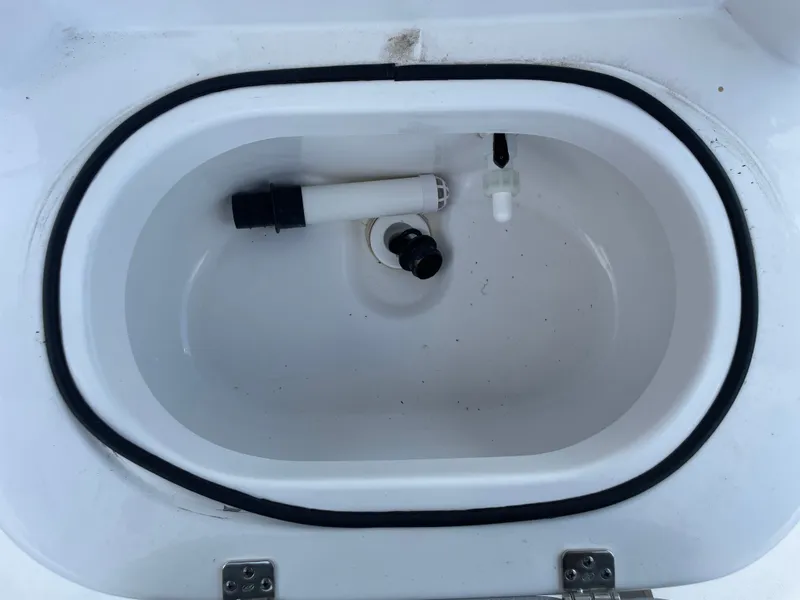 Slide: The Image of 2024 NauticStar 191H livewell with plumbing components, white interior. - 19