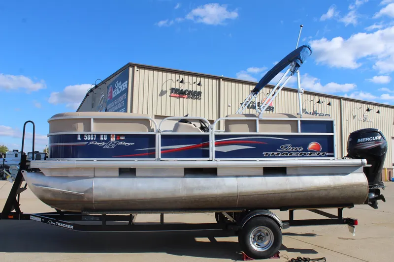 Slide: The Image of 2016 Sun Tracker Party Barge 16 DLX pontoon boat on trailer, blue sky background. - 4