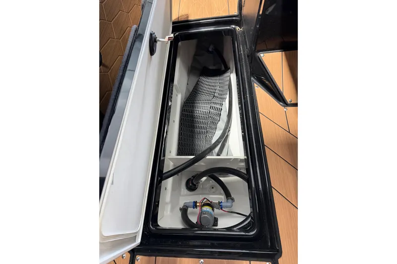 Slide: The Image of Open storage compartment in 2026 Yamaha Boats 255 XD, showcasing interior components and wiring. - 27