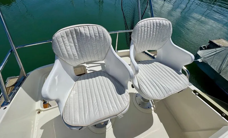 Slide: The Image of Two white cushioned seats on a 2004 Rodman 800 boat deck. - 12
