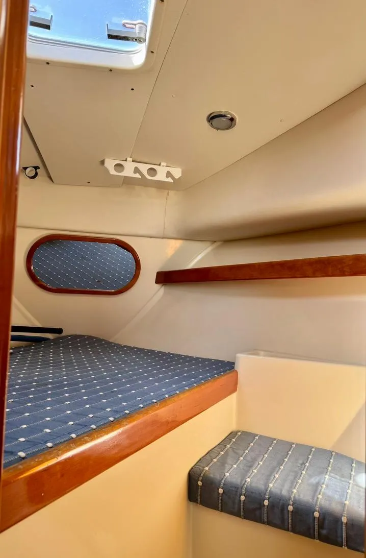 Slide: The Image of Interior cabin of 2004 Rodman 800 boat with blue cushioned seating and wooden accents. - 20