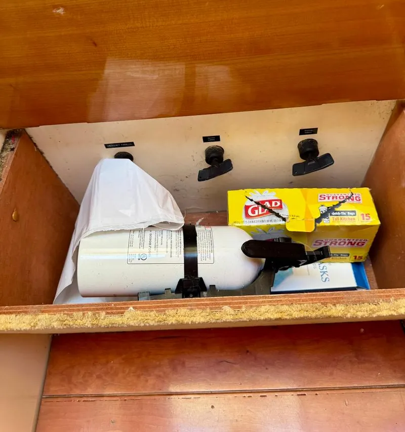 Slide: The Image of Storage compartment with fire extinguisher and Glad trash bags on a 2004 Rodman 800 boat. - 28