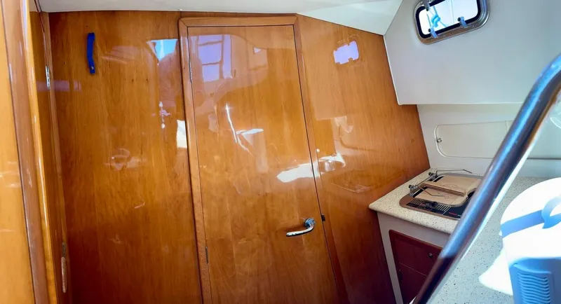 Slide: The Image of Interior of a 2004 Rodman 800 boat with wooden paneling and a small window. - 31