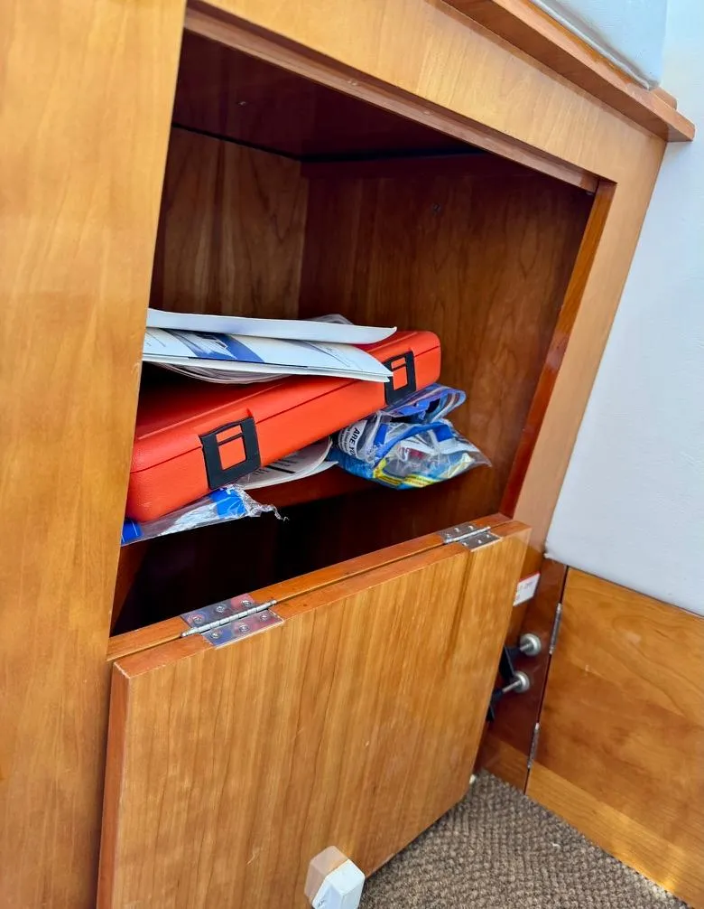 Slide: The Image of Wooden cabinet with open door, containing documents and a red case, in a 2004 Rodman 800. - 34