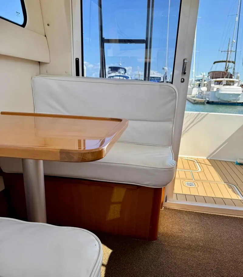 Slide: The Image of Interior of a 2004 Rodman 800 boat with white seating and wooden table. - 37