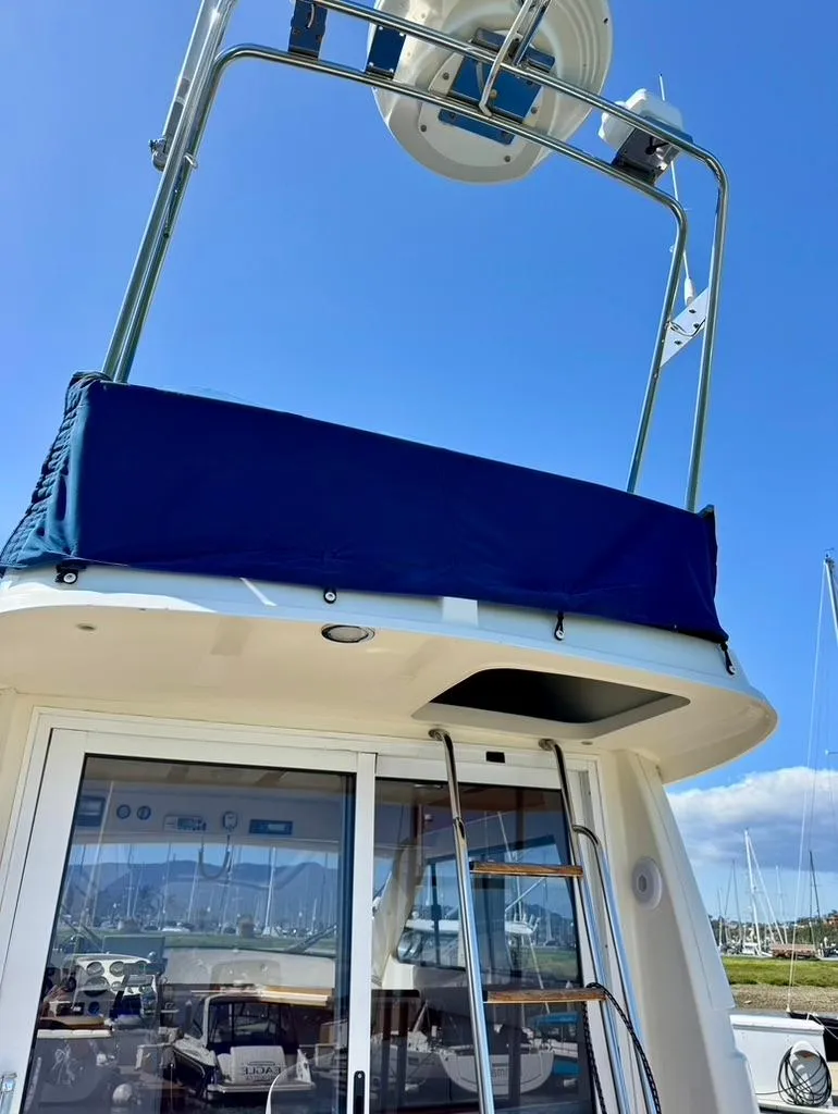 Slide: The Image of 2004 Rodman 800 boat with upper deck and ladder, docked at marina under clear blue sky. - 9
