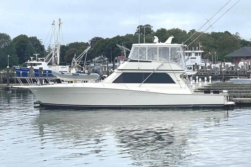 The Image of 1991 Viking 53 Convertible yacht docked at a marina, surrounded by calm water and other boats. - 0
