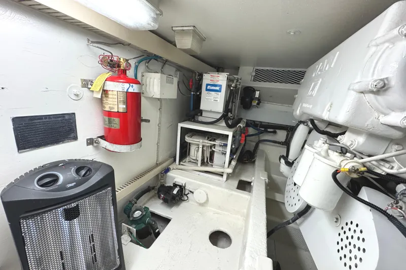 Slide: The Image of Engine room of 1991 Viking 53 Convertible yacht, featuring equipment and fire extinguisher. - 69