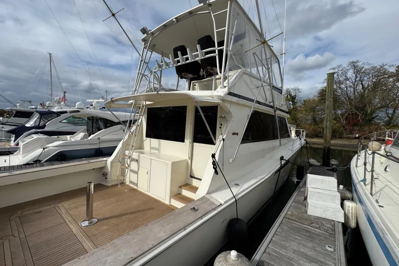 Slide: The Image of 1991 Viking 53 Convertible yacht docked at marina, showcasing spacious deck and flybridge. - 9