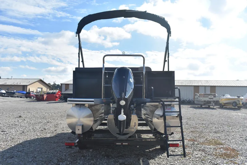 Slide: The Image of 2026 Lowe LS 210 pontoon boat with outboard motor, parked on gravel lot. - 4
