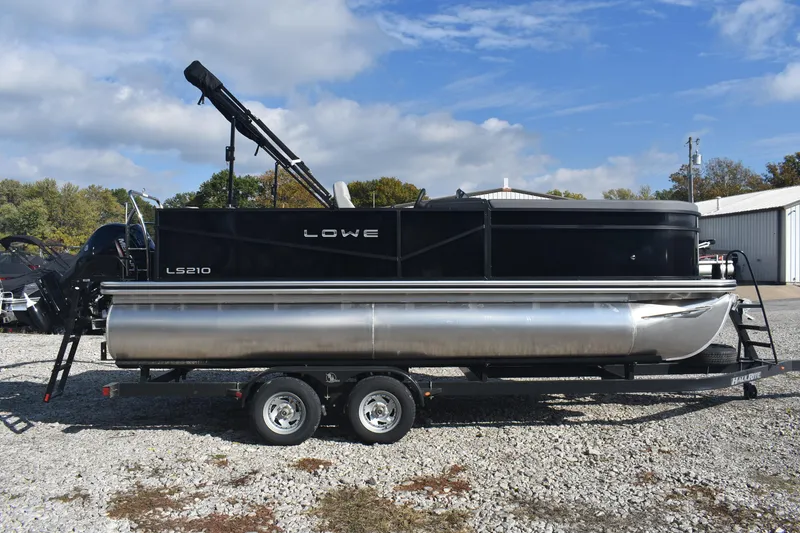 Slide: The Image of 2026 Lowe LS 210 pontoon boat on trailer, parked outdoors under a cloudy sky. - 6