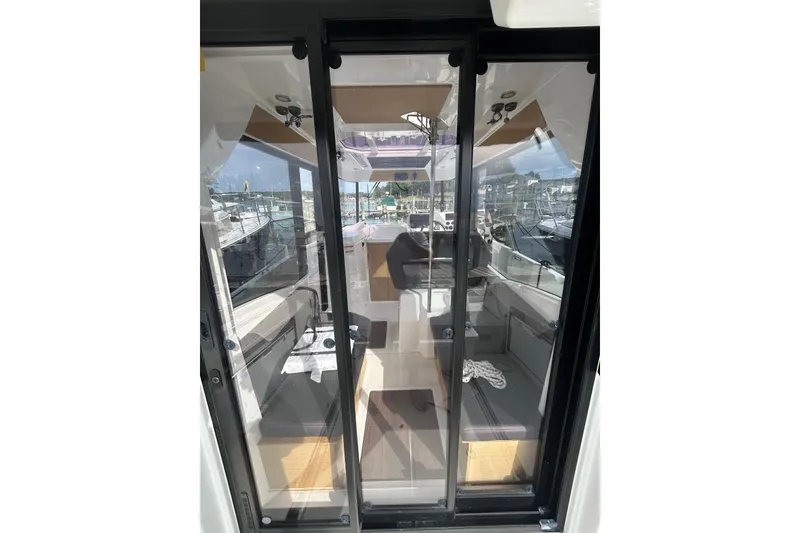 Slide: The Image of 2020 Beneteau Barracuda 9 interior view through glass doors, showcasing seating and helm. - 3