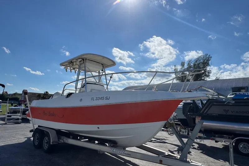 The Image of 2002 Aquasport 225 Osprey boat on trailer under clear blue sky. - 0