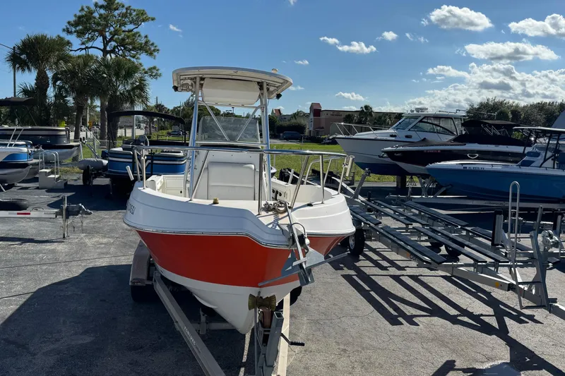 Slide: The Image of 2002 Aquasport 225 Osprey boat on trailer, surrounded by other boats, under a clear blue sky. - 1