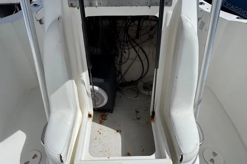 Slide: The Image of 2002 Aquasport 225 Osprey boat interior with exposed wiring and white seating. - 18