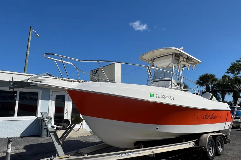 Slide: The Image of 2002 Aquasport 225 Osprey boat on trailer, red and white design, clear blue sky. - 2