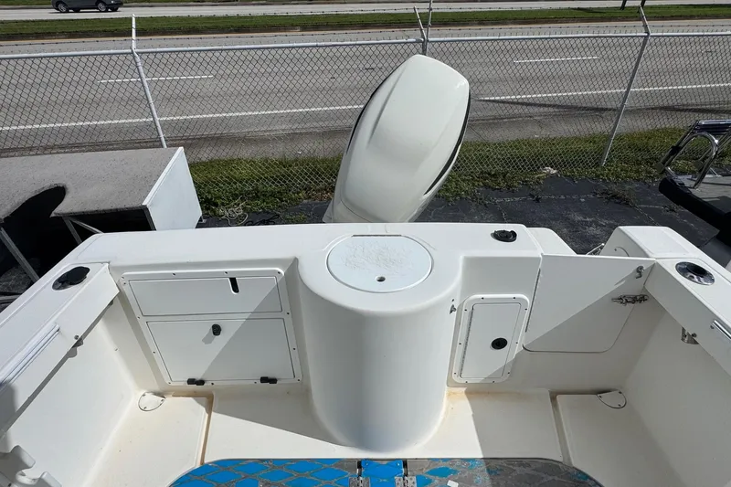 Slide: The Image of 2002 Aquasport 225 Osprey boat interior with storage compartments and motor, near a highway. - 20