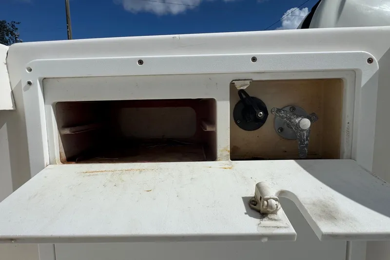 Slide: The Image of 2002 Aquasport 225 Osprey boat compartment with open hatch and control knobs. - 23