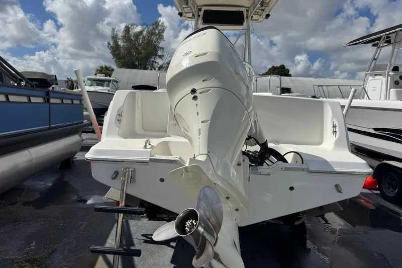 Slide: The Image of 2002 Aquasport 225 Osprey boat with outboard motor, docked under a cloudy sky. - 27