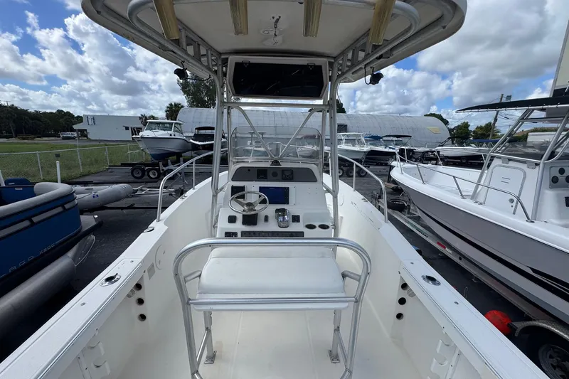 Slide: The Image of 2002 Aquasport 225 Osprey boat interior with steering console and seating, docked outdoors. - 4