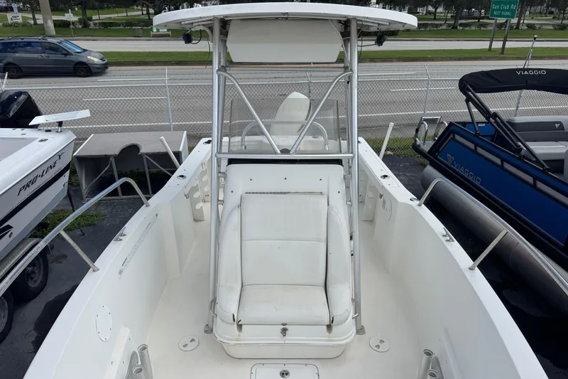 Slide: The Image of 2002 Aquasport 225 Osprey boat with white seating and T-top, parked near road. - 6