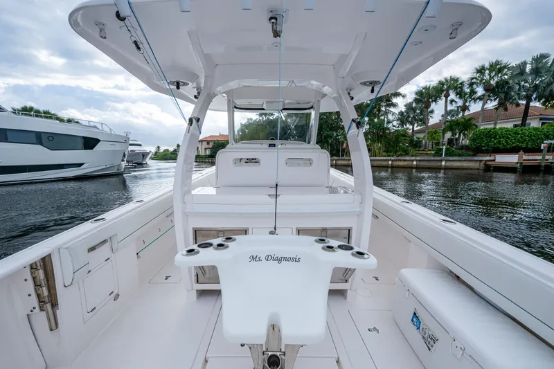 Slide: The Image of 2020 Intrepid 407 Panacea boat interior with fishing rod holders, docked near waterfront homes. - 14