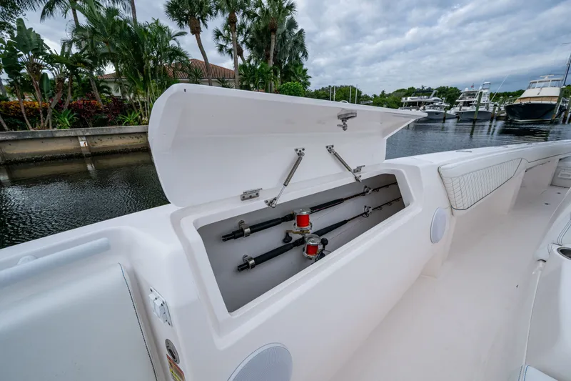 Slide: The Image of 2020 Intrepid 407 Panacea boat with open storage compartment, fishing rods visible, docked near palm trees. - 29