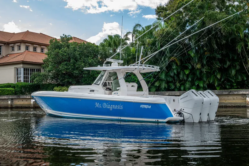 Slide: The Image of 2020 Intrepid 407 Panacea boat with blue hull, docked near a house. - 45