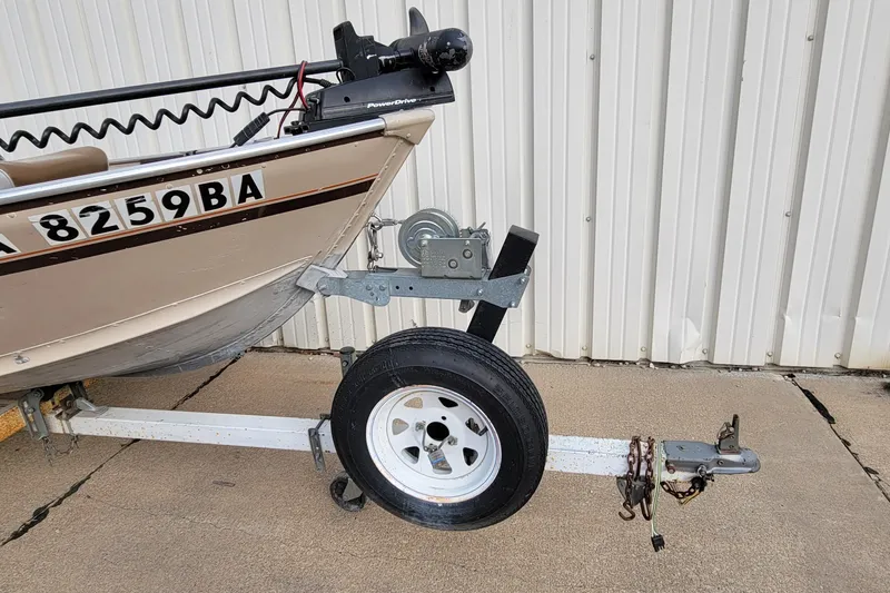 Slide: The Image of 1987 Alumacraft Classic 165 CS boat on trailer, parked by a corrugated metal wall. - 20
