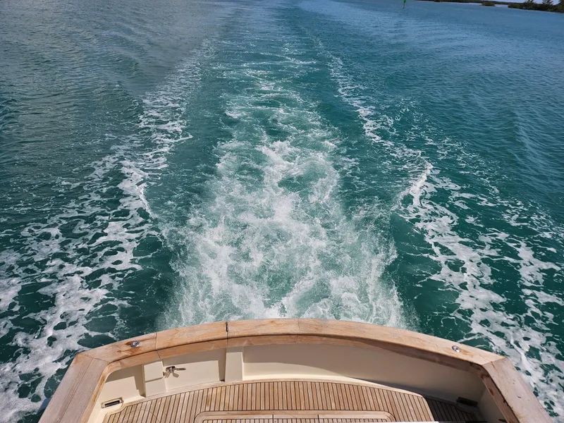 Slide: The Image of View from the stern of a 1991 Donzi 65 Sportfisherman boat cruising on clear blue water. - 21