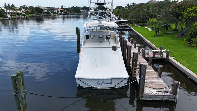 Slide: The Image of 1991 Donzi 65 Sportfisherman docked in a serene waterfront setting. - 38