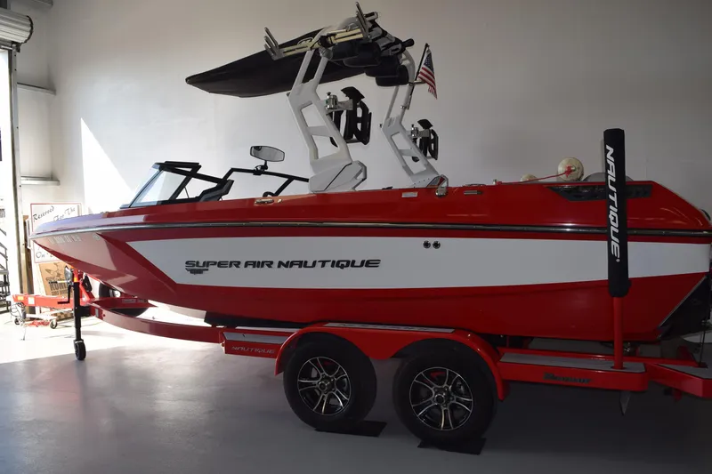 Slide: The Image of 2021 Nautique Super Air Nautique GS22 boat in a garage, red and white design. - 1