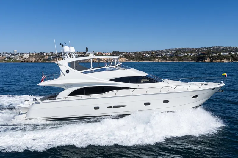 Slide: The Image of Luxury 2005 Marquis 65 yacht cruising on ocean near coastal cityscape. - 2