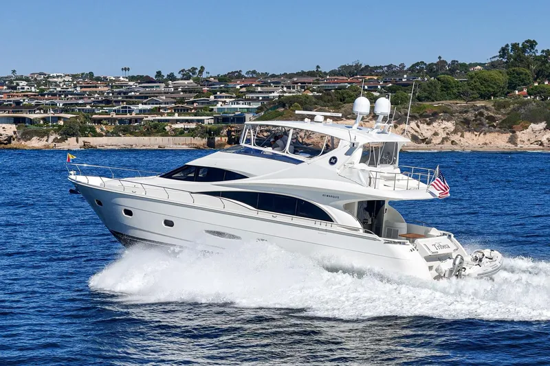 Slide: The Image of Luxury 2005 Marquis 65 yacht cruising on blue ocean near coastal homes. - 8